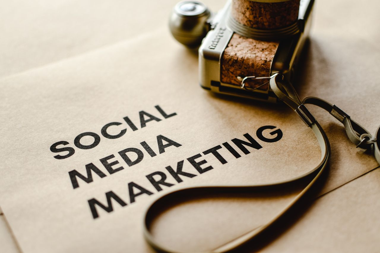 Vue rapprochée d’un appareil photo posé sur du papier brun avec le texte Social Media Marketing, mettant en avant les thèmes du marketing numérique.